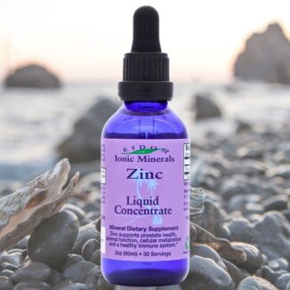 Flaske med Eidon Ionic Minerals flytende mineraltilskudd Sink flytende 60 ml plassert på steinstrand, blå pipetteflaske.